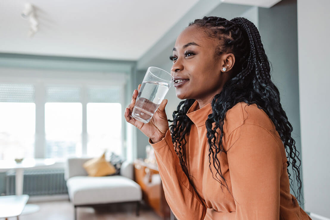 Woman drinks a glass of tasteful filtered water.