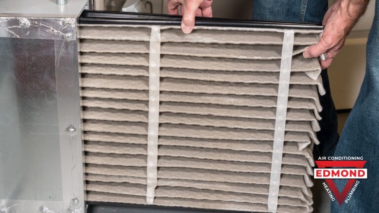 Technician removing a heavily clogged air filter from a residential heating system during furnace maintenance